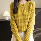A woman wearing a long sleeve yellow off shoulder merino wool sweater with a ribbed neck.