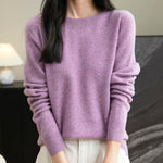 A woman wearing a long sleeve merino wool purple crewneck sweater.