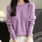 A woman wearing a long sleeve merino wool purple crewneck sweater.