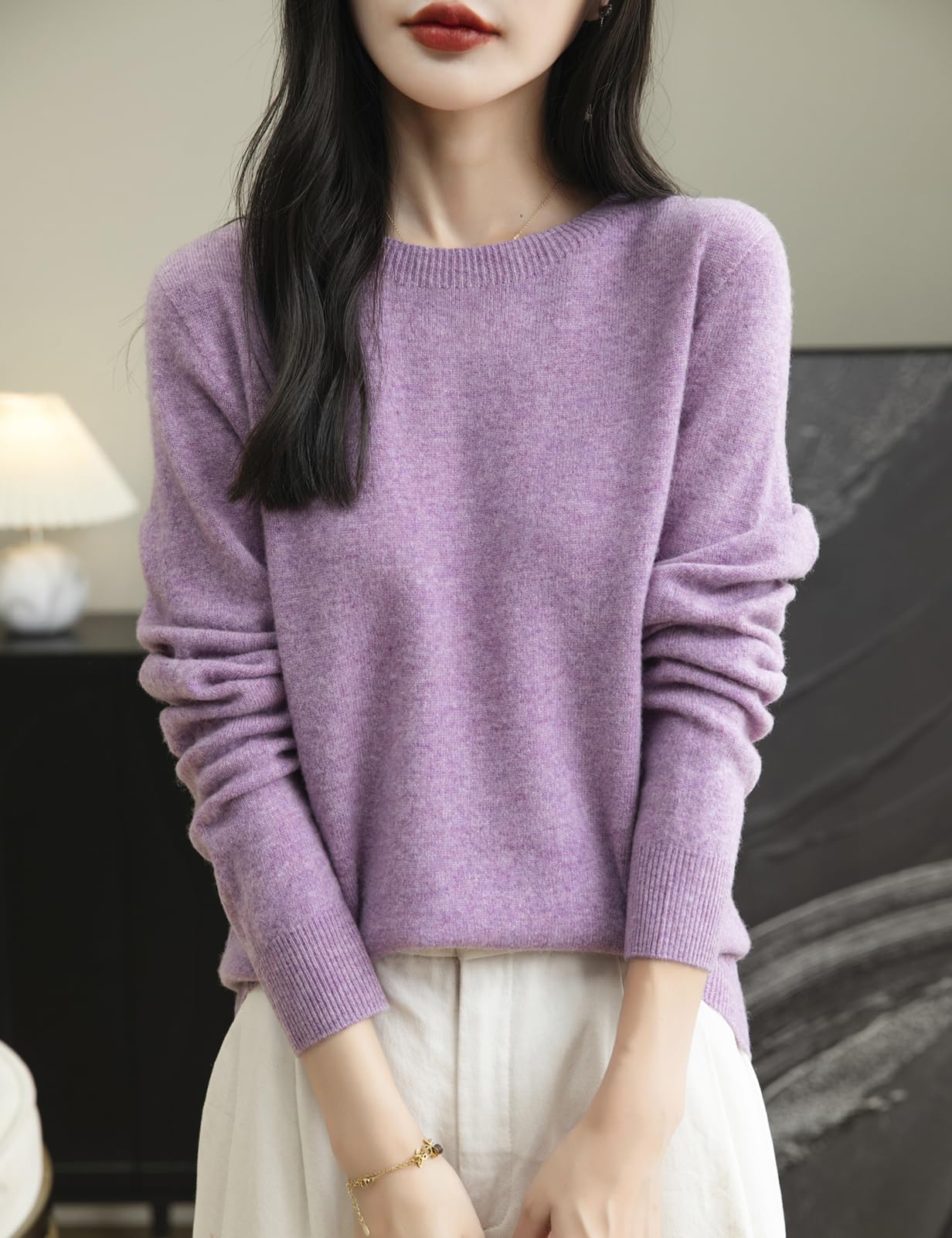 A woman wearing a long sleeve merino wool purple crewneck sweater.