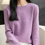 Woman wearing a 100% merino wool navy blue crewneck sweater while sitting