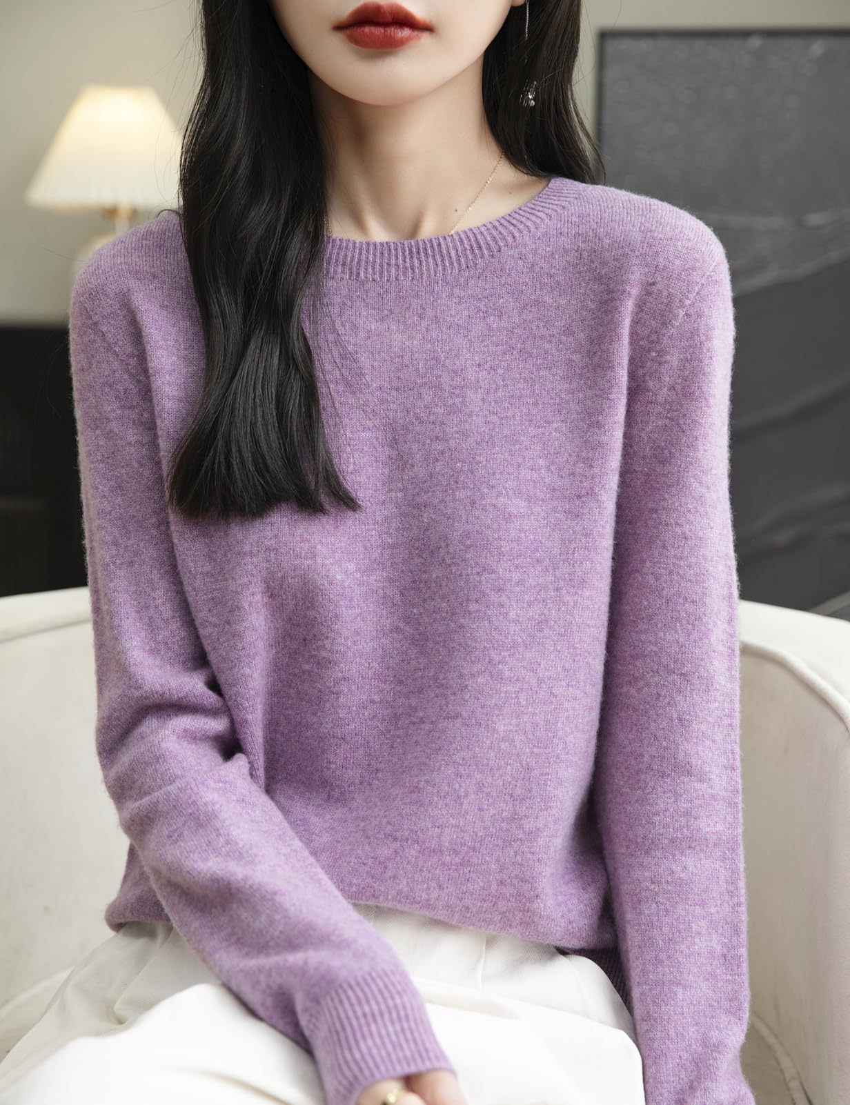 Woman wearing a 100% merino wool navy blue crewneck sweater while sitting