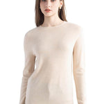 A woman wearing a long sleeve merino wool beige crewneck sweater.