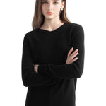 A woman wearing a long sleeve merino wool black crewneck sweater.