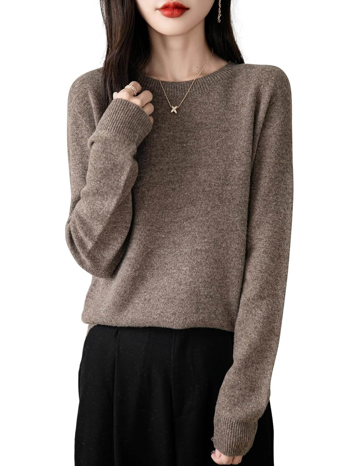 A woman wearing a long sleeve merino wool brown crewneck sweater.