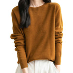 A woman wearing a long sleeve merino wool caramel crewneck sweater.