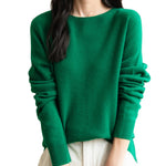 A woman wearing a long sleeve merino wool green crewneck sweater.