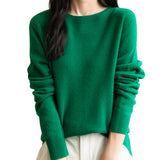 A woman wearing a long sleeve merino wool green crewneck sweater.