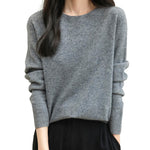A woman wearing a long sleeve merino wool grey crewneck sweater.