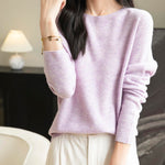 A woman wearing a long sleeve merino wool light purple crewneck sweater.