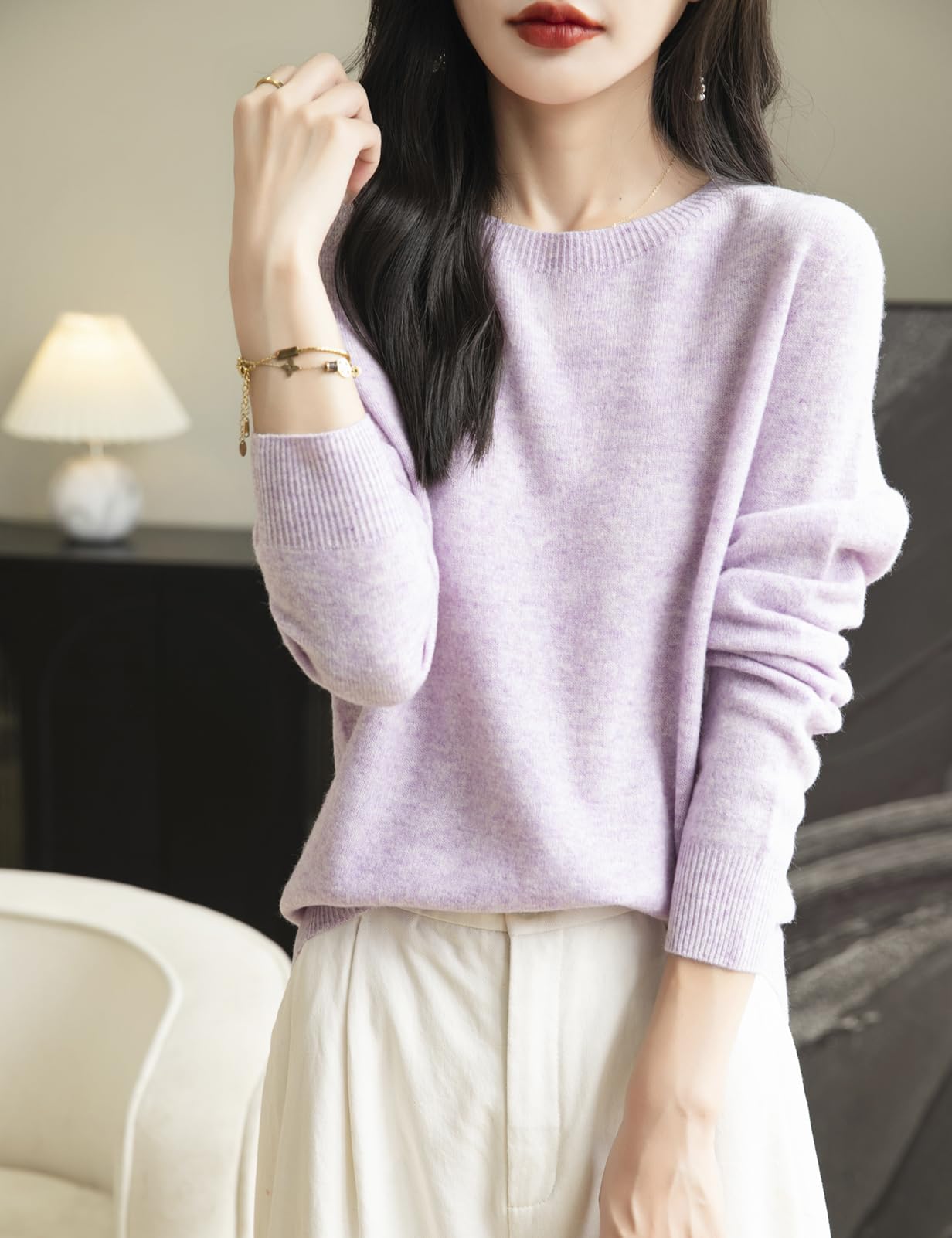 A woman wearing a long sleeve merino wool light purple crewneck sweater.