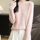 A woman wearing a long sleeve merino wool pink crewneck sweater.