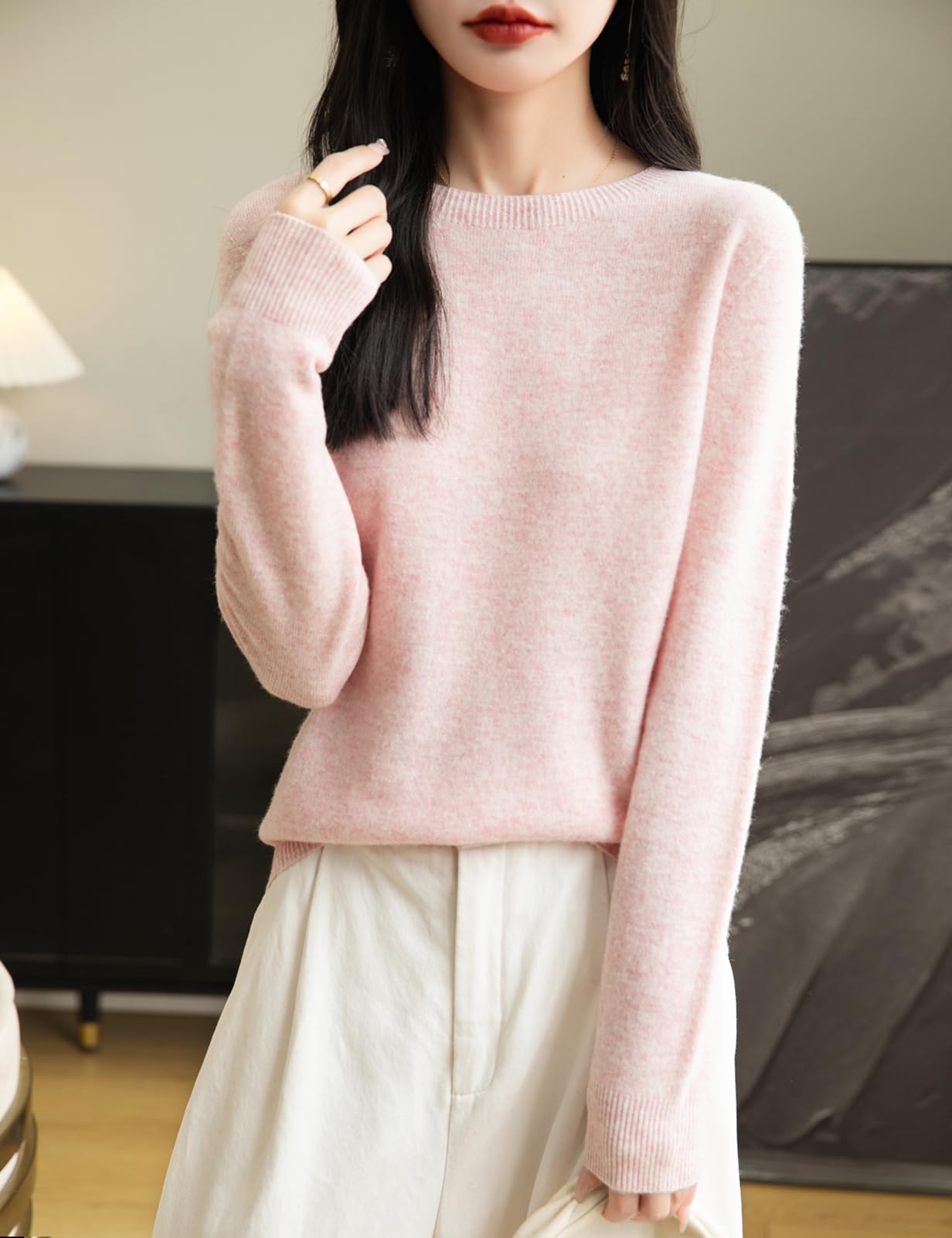 A woman wearing a long sleeve merino wool pink crewneck sweater.