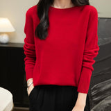 A woman wearing a long sleeve merino wool red crewneck sweater.