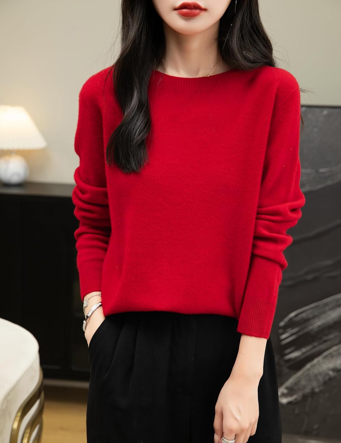 A woman wearing a long sleeve merino wool red crewneck sweater.