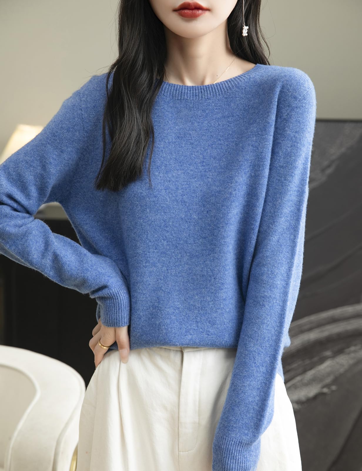 A woman wearing a long sleeve merino wool star blue crewneck sweater.