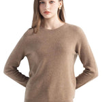 A woman wearing a long sleeve merino wool tan crewneck sweater.