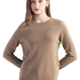 A woman wearing a long sleeve merino wool tan crewneck sweater.