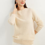 A woman wearing a beige, long-sleeved, crew neck cashmere sweater.