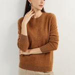 A woman wearing a caramel, long-sleeved, crew neck cashmere sweater.