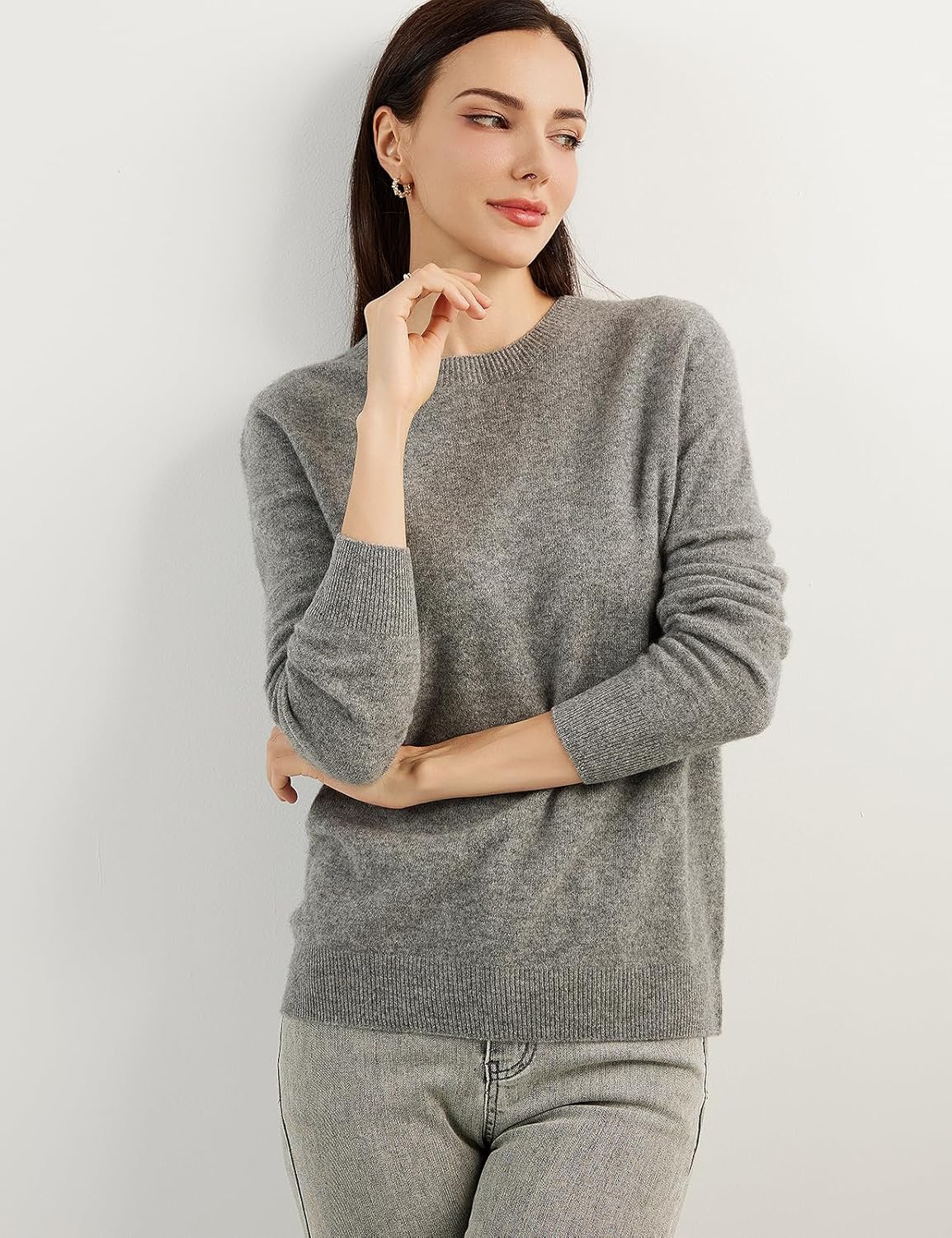 A woman wearing a grey, long-sleeved, crew neck cashmere sweater.