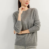 A woman wearing a grey, long-sleeved, crew neck cashmere sweater.