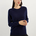 A woman wearing a navy blue, long-sleeved, crew neck cashmere sweater.