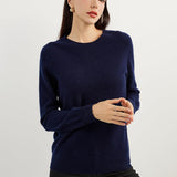 A woman wearing a navy blue, long-sleeved, crew neck cashmere sweater.