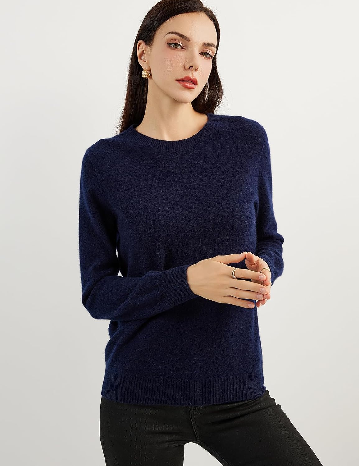 A woman wearing a navy blue, long-sleeved, crew neck cashmere sweater.