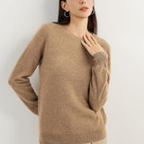 A woman wearing a tan,  long-sleeved, crew neck cashmere sweater.