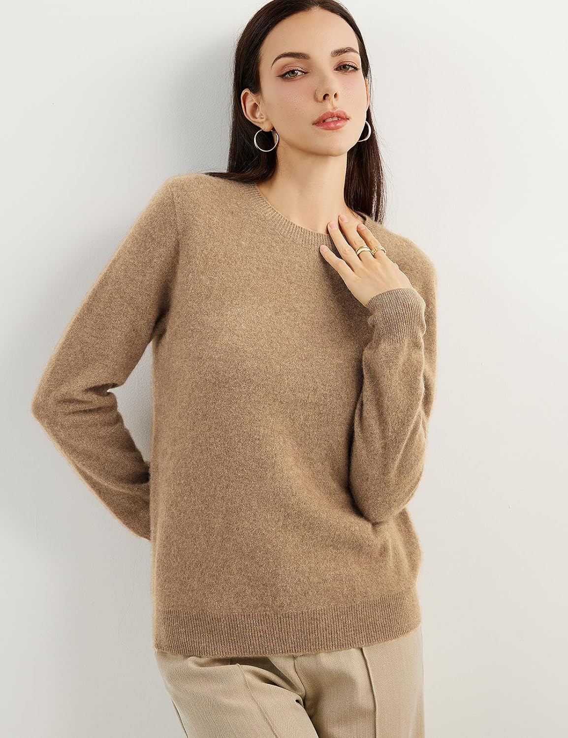 A woman wearing a tan,  long-sleeved, crew neck cashmere sweater.